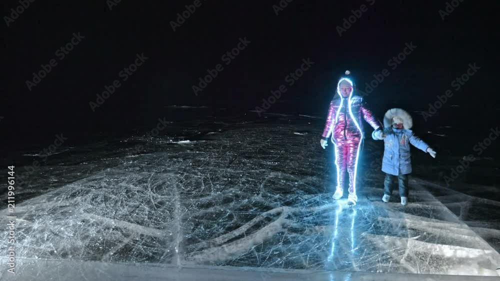 Family is ice skating night. Girls and boys to ride figure ice skates in nature. Mother daughter and son riding together on ice in cracks. Outdoor winter fun for athlete nice winter weather. People on Family is ice skating night. Girls and boys to ride figure ice skates in nature. Mother daughter and son riding together on ice in cracks. Outdoor winter fun for athlete nice winter weather. People on
