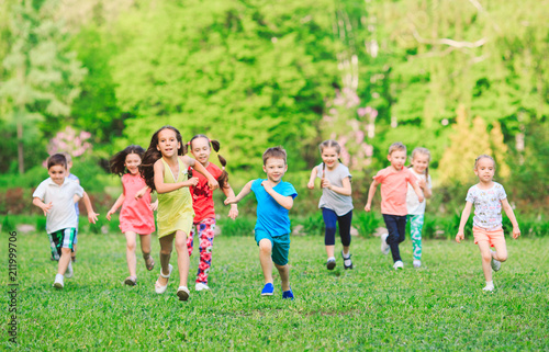 Many different kids, boys and girls running in the park on sunny summer day in casual clothes