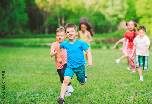 Many different kids, boys and girls running in the park on sunny summer day in casual clothes