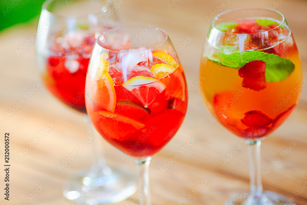 Summer cocktail. Fruit cocktail on green background. Citrus fruits, berries, strawberries, blueberries, mint, ice.