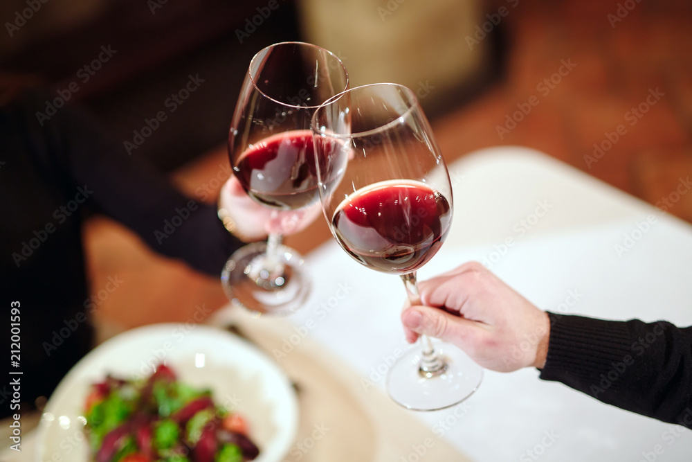 Obraz premium Man and woman drinking red wine. In the picture, close-up hands with glasses.