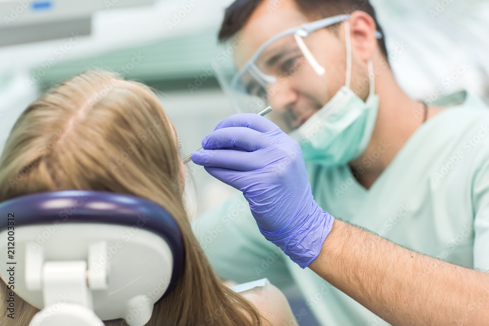 Close-up picture of young woman sitting in the dentist's chair with opened mouth at dentist's office while having examination. Close-up picture of young woman sitting in the dentist's chair with opened mouth at dentist's office while having examination.