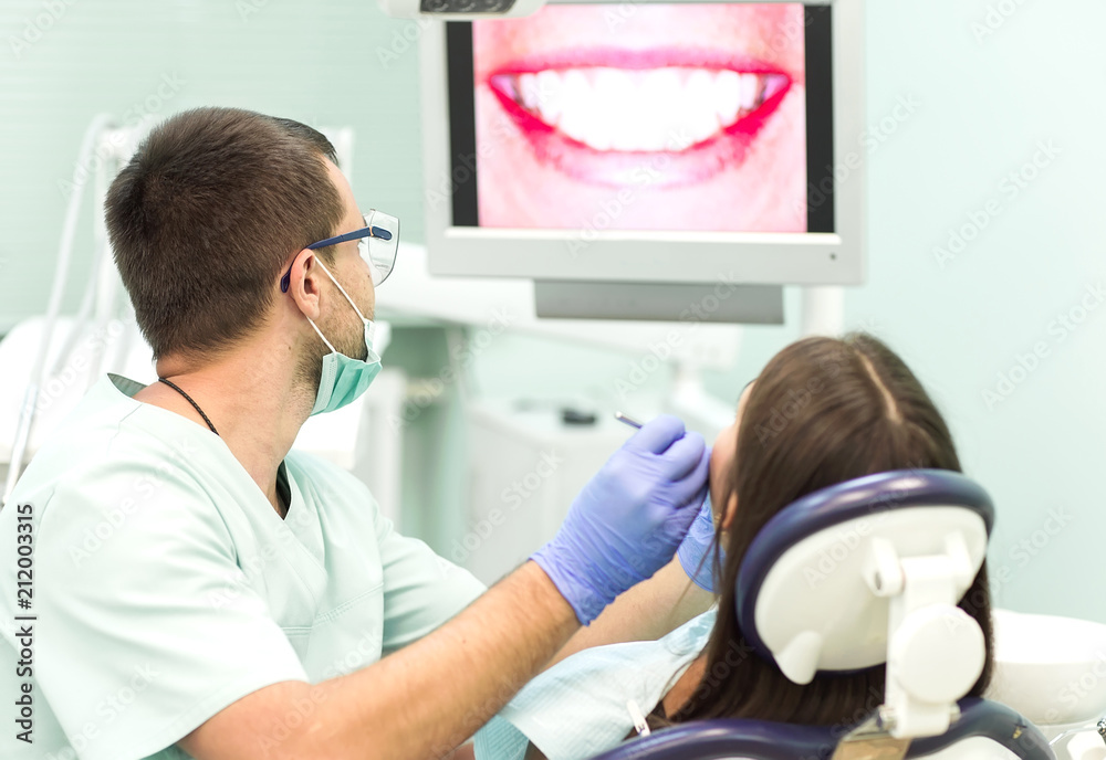 young woman sitting in the dentist's chair with opened mouth at dentist's office while having examination. young woman sitting in the dentist's chair with opened mouth at dentist's office while having examination.