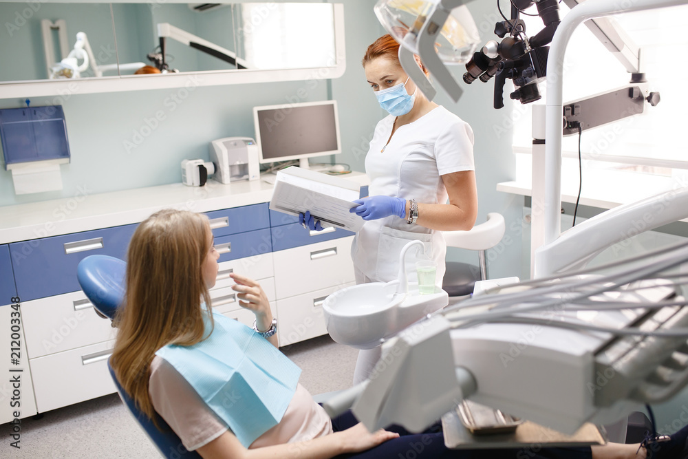 female dentist with patient girl talking at dental clinic office female dentist with patient girl talking at dental clinic office
