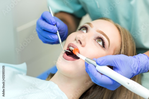 Dentist doing procedure with dental curing UV light in clinic