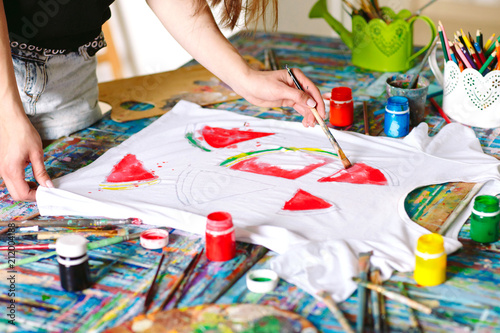 Drawing on clothes. Girl draws on a white T-shirt.