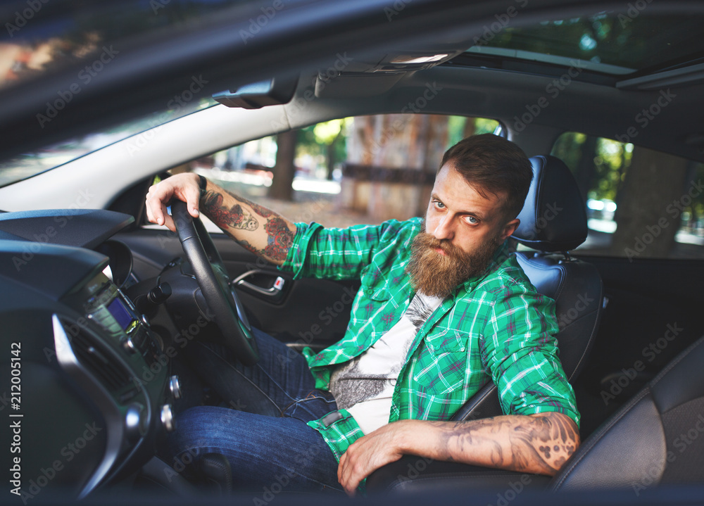 A bearded man in a new car.