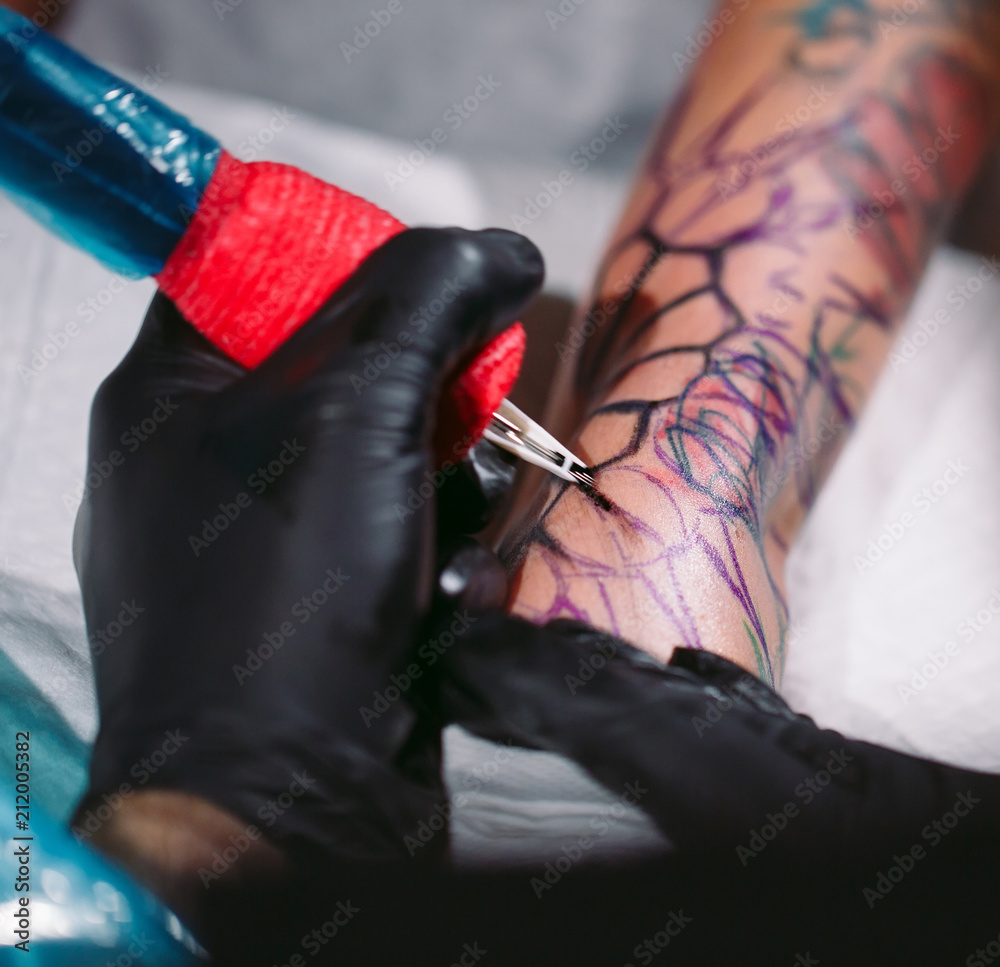 Professional tattoo artist makes a tattoo on a young girl's hand. Stock ...