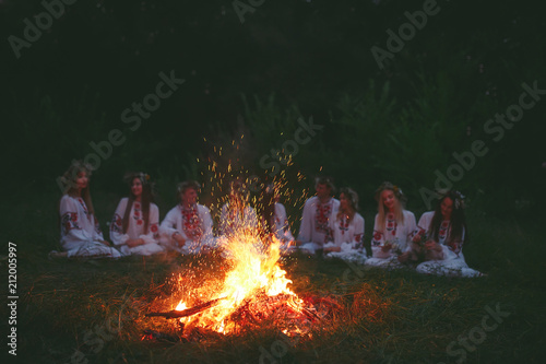 Midsummer night. Young people in Slavic clothes sitting near the bonfire.