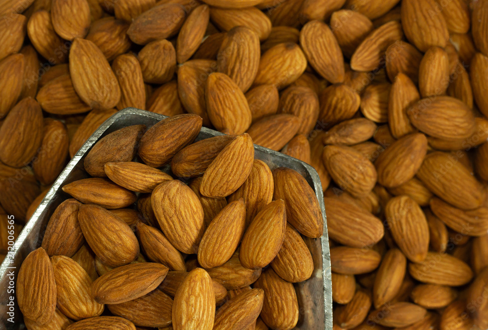 Fototapeta premium almond nuts on stainless scoop . brown color beans background .