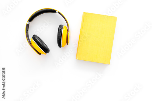 Books online concept, audiobooks. Spend leasure time reading and listening music. Headphones near hardback book with empty cover on white background top view copy space