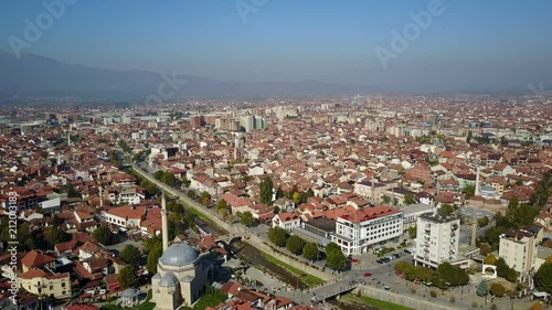 Establishing drone shot of downtown Prizren, with low-rise apartment buildings, a mosque, and various other structures photo