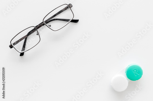 Way to improve vision. Contact lenses in container near glasses on white background top view copy space