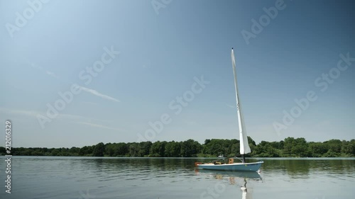 Sailboat luffing in wind while anchored offshore.