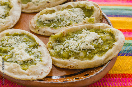 Mexican sopes with grated cheese and green salsa, mexican food spicy in mexico