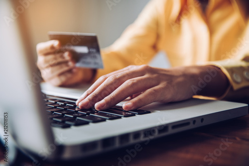 Hand holding a credit card in their hands and find information about a product using their mobile device to make purchases online and conduct financial transactions.