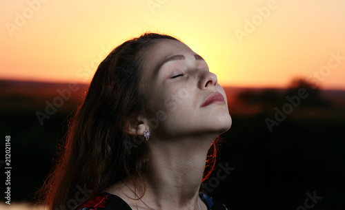 beautiful girl with eyes closed on sunset background