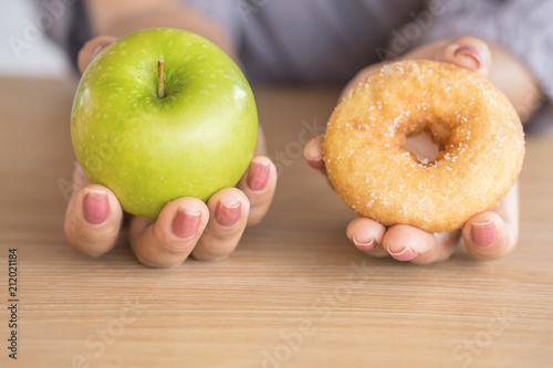 woman hands holding green apple and donut  ,healthy or unhealthy eating concept  photo