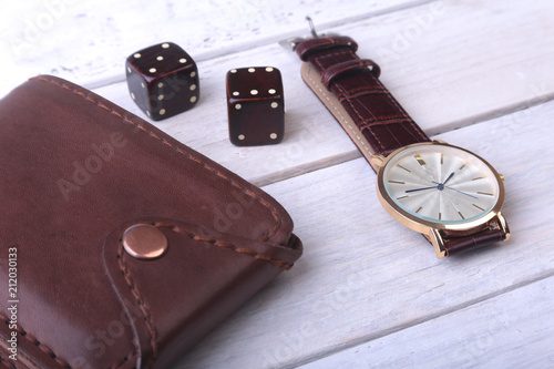 Men's accessories for business and rekreation. Watch, leather wallet and dice on wood background.. Top view composition.