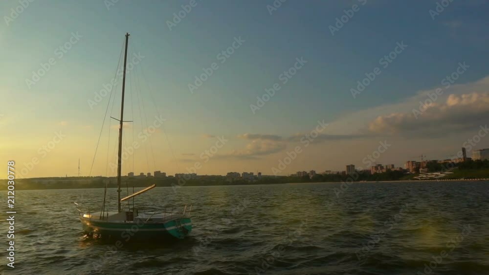 A small sailboat on the quay in the city bay, sunset, beautiful evening landscape, slow motion A small sailboat on the quay in the city bay, sunset, beautiful evening landscape, slow motion