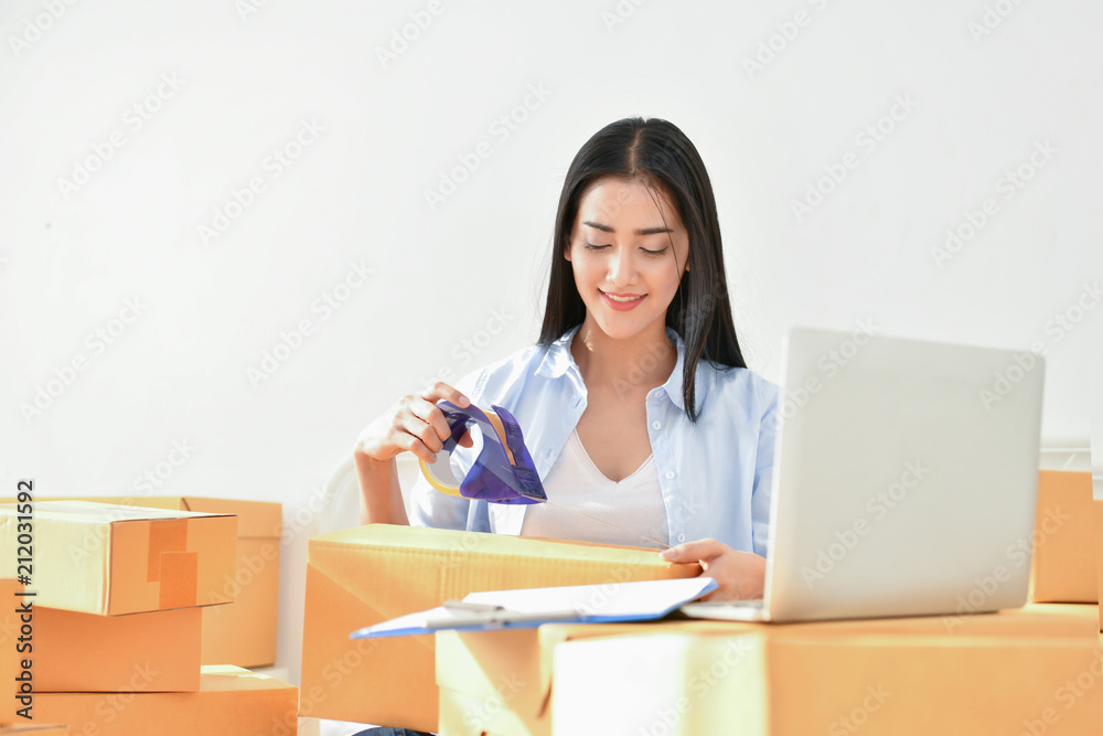 Sme business concept. Young people are packing their packages.Delivery business Small and Medium Enterprise (SMEs). Young woman is working in the house.Young Owner Start up for Business Online. Sme business concept. Young people are packing their packages.Delivery business Small and Medium Enterprise (SMEs). Young woman is working in the house.Young Owner Start up for Business Online.