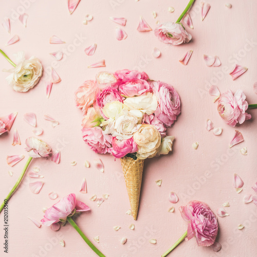 Flat-lay of waffle sweet cone with pink and white buttercup flowers over pastel light pink background, top view, square crop. Spring or summer mood concept