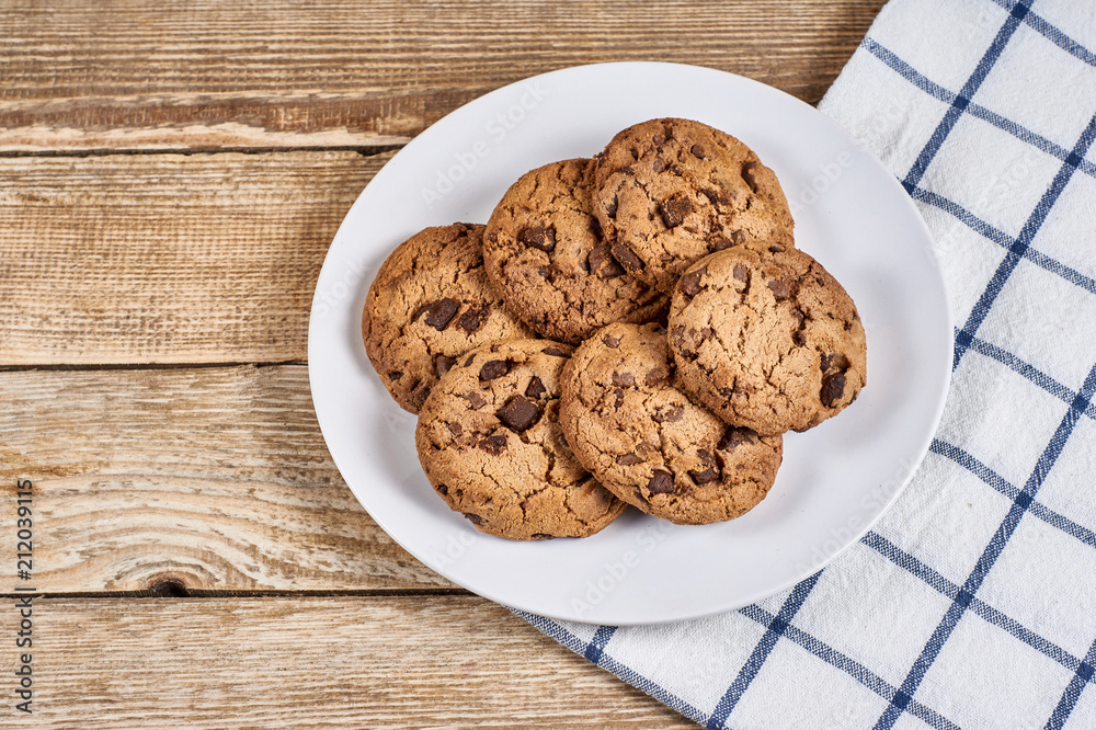 oatmeal cookies with chocolate slices in white plate and napkin on a wooden background oatmeal cookies with chocolate slices in white plate and napkin on a wooden background