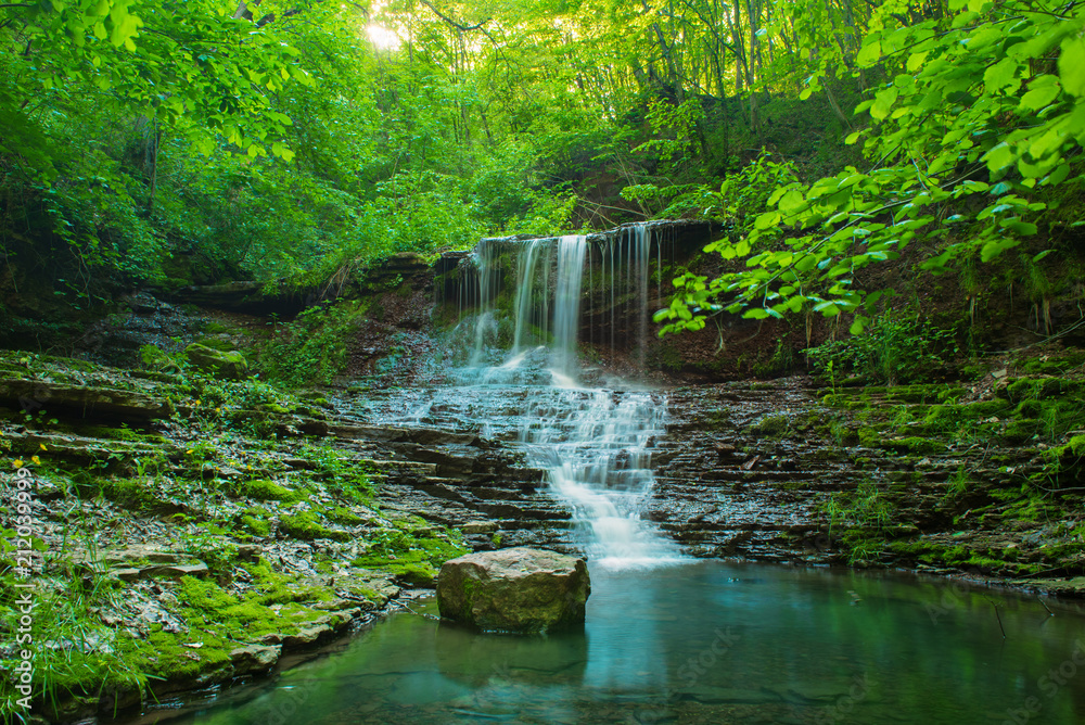 Beautiful mountain rainforest waterfall with fast flowing water and rocks, long exposure. Natural seasonal travel outdoor background in hipster vintage style Beautiful mountain rainforest waterfall with fast flowing water and rocks, long exposure. Natural seasonal travel outdoor background in hipster vintage style