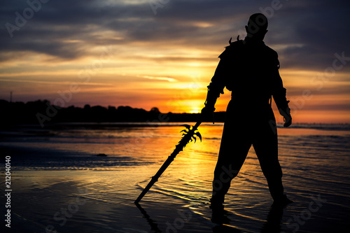 Silhouette of assassin with the sword at the beach. He is posing at the sea d...