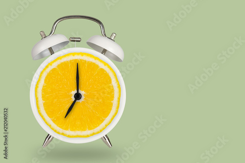 Creative fresh lime slice alarm clock on pastel green background, idea concept