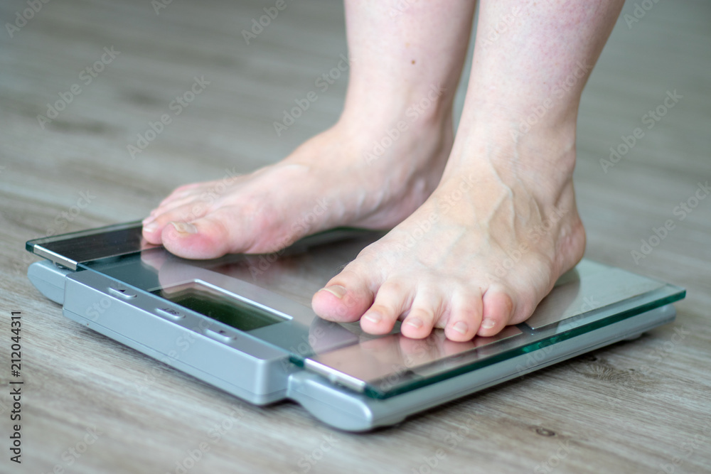 Woman standing on a scale in the bathroom Woman standing on a scale in the bathroom