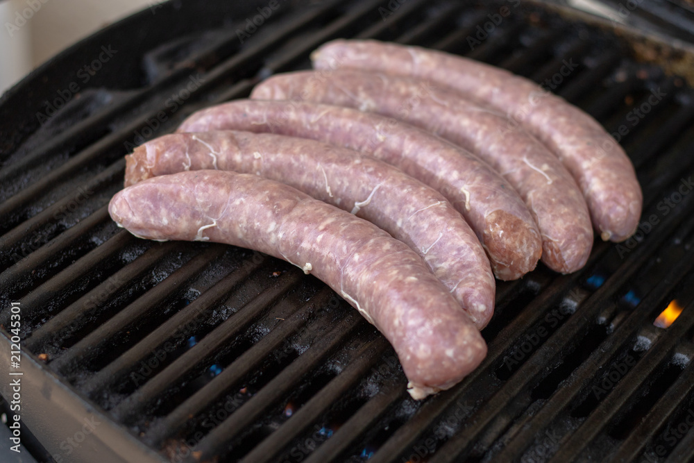 Five raw sausages lying on the grill for barbecue