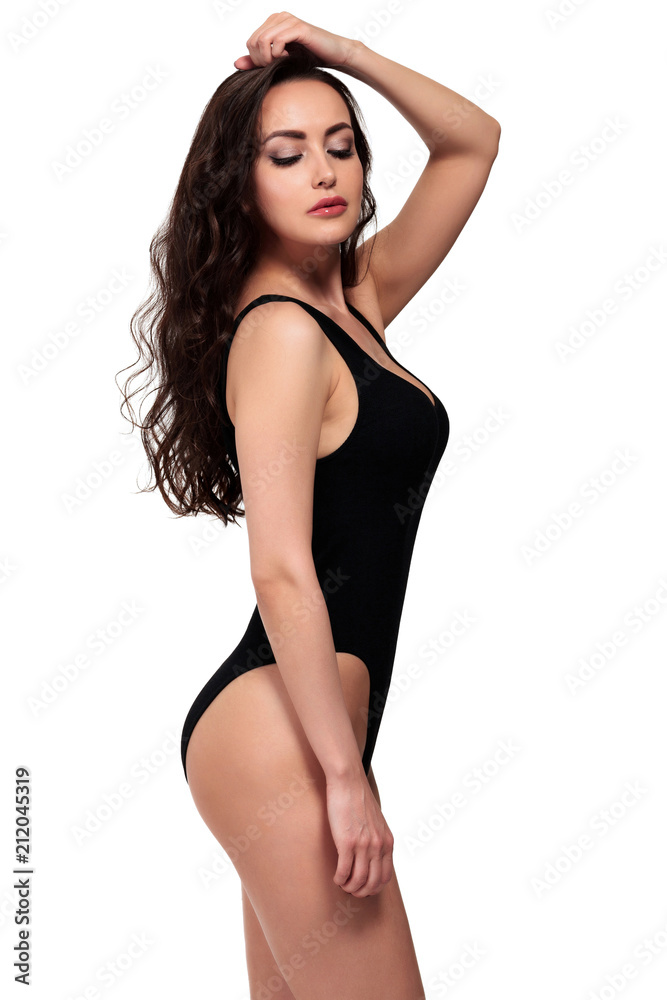 Pretty girl in black swimsuit is posing against a white background, isolated
