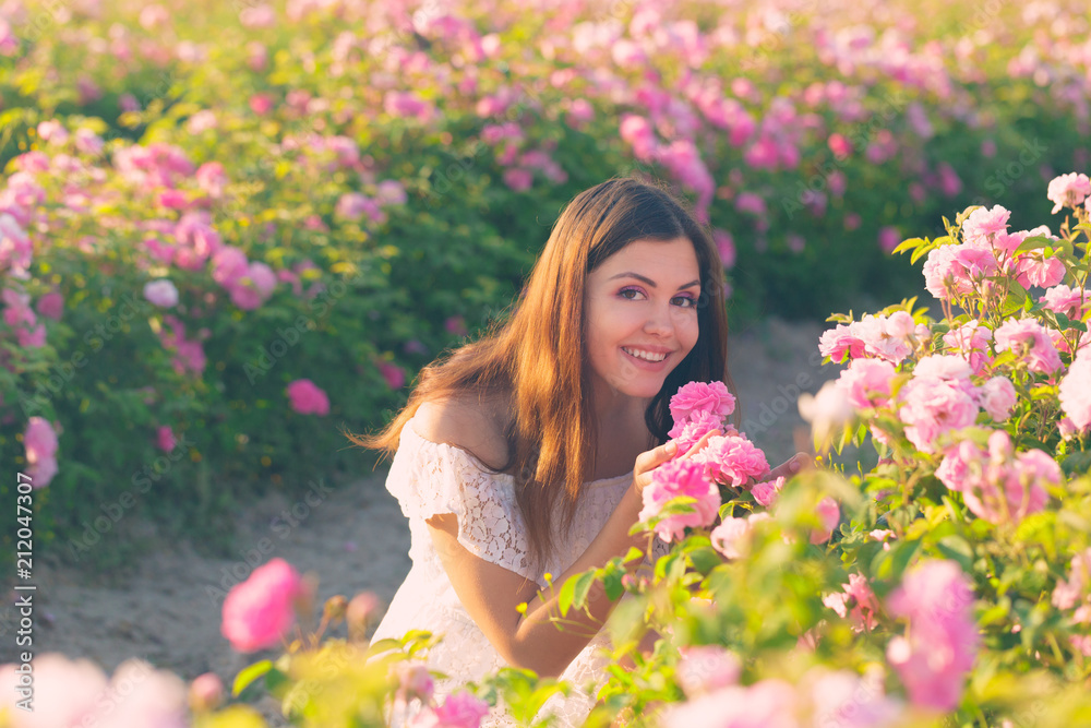 Beautiful young woman posing near roses in a garden. Beautiful young woman posing near roses in a garden.