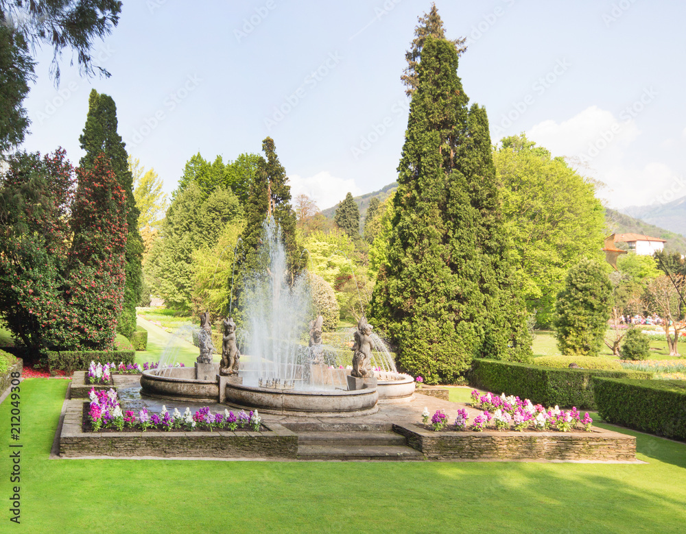 Beautiful fountain, water fountain with statue europe style in the park with flowers in spring nature background.