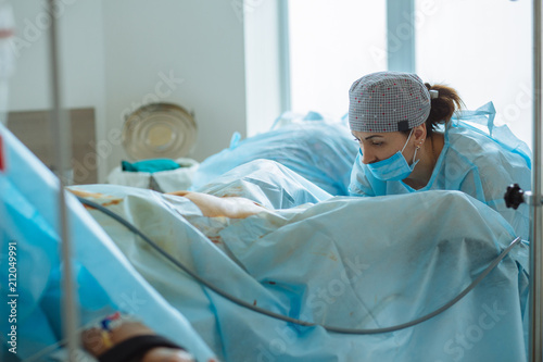 Female gynecologist preparing patient for laparoscopy operation. Real people models.