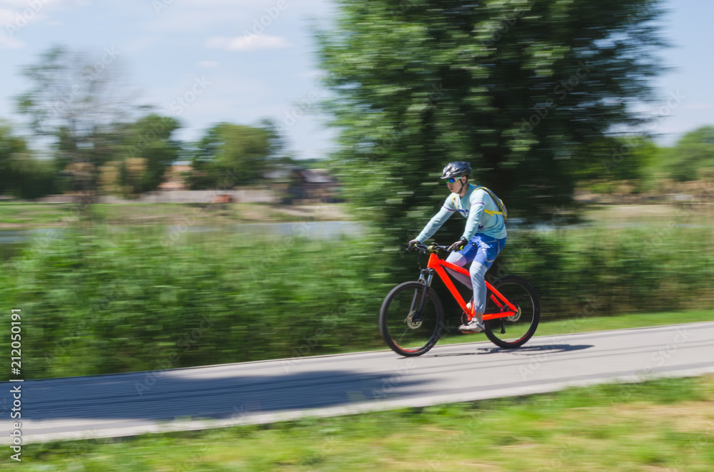 Obraz premium A cyclist in a helmet rides a bicycle path, motion blur