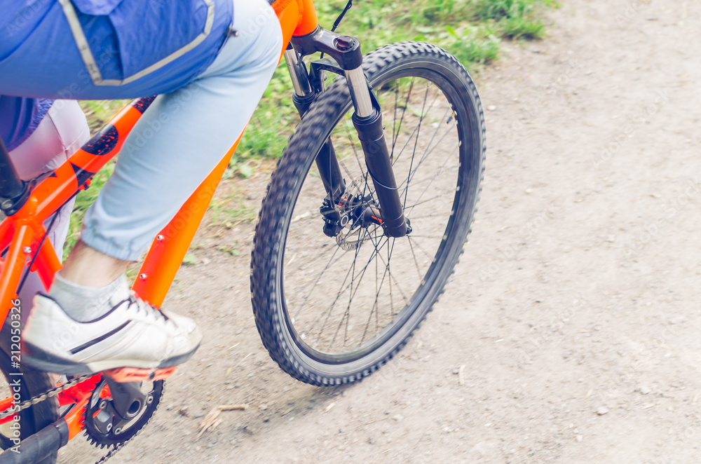 Naklejka premium Cyclist on an orange bike riding a bicycle path