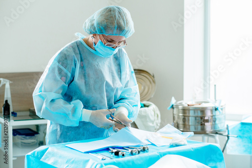 Female assistant near table with equipment prepating for laparoscopy operation. Real people models.