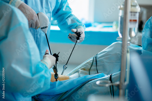 Unrecognizable surgeon's holing the instrument in abdomen of patient. The surgeon's doing laparoscopic surgery in the operating room. Minimally invasive surgery. Close up photo