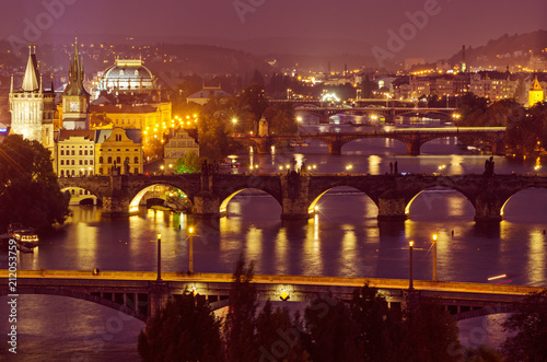 Night view of famous european Prague city - the capital of Czech republic with reflection in river Vltava and historical bridges