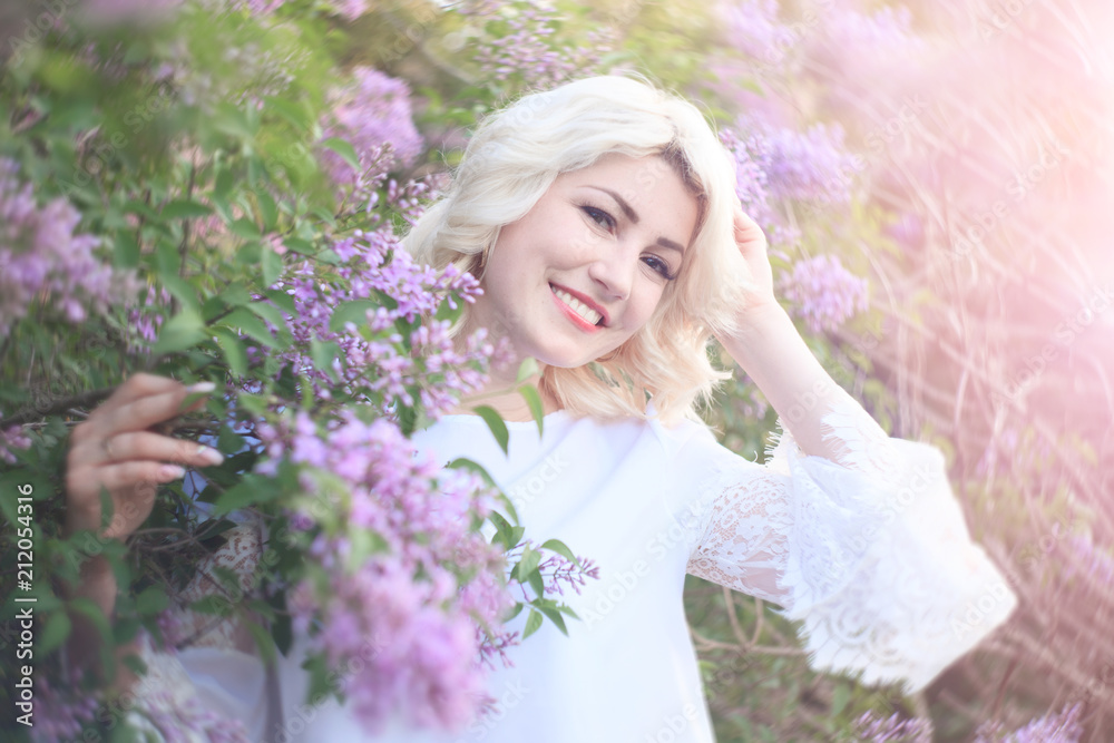 Fototapeta premium Beautiful woman in a spring garden with blooming lilacs.