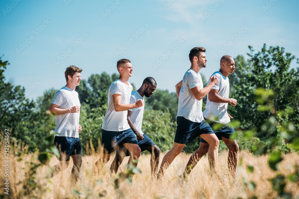 Side view of multicultural group of soldiers running on range Side view of multicultural group of soldiers running on range
