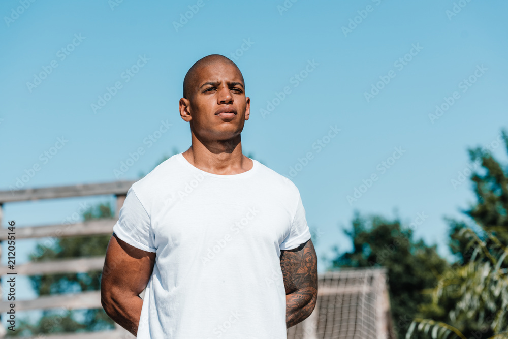 portrait of african american tattooed soldier in white shirt standing on range