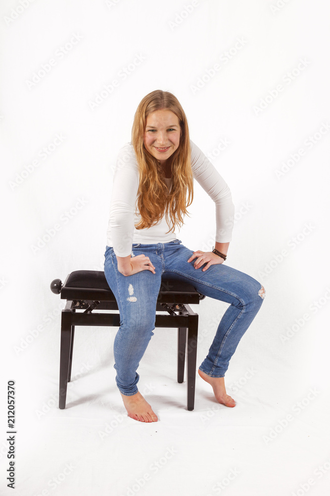 young teenage girl sitting on a piano chair young teenage girl sitting on a piano chair