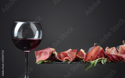 Prosciutto with figs, rosemary and glass of red wine .