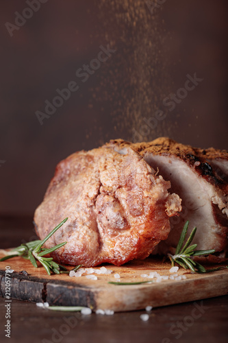 Oven-baked pork with rosemary and spices on a wooden table.
