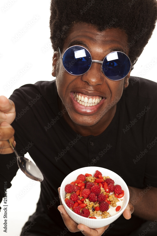 young handsome afro american guy hipster eating cereals woth fresh fruits isolated on white background. healthy food concept