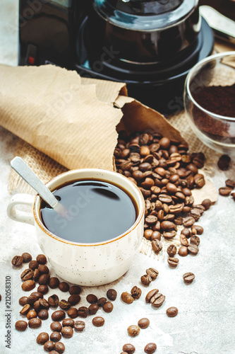 Variety things for prepare coffee. Roasted beans, ground coffee, scoop, electric coffee machine and assortment of sweets and spices to eat with on light background.