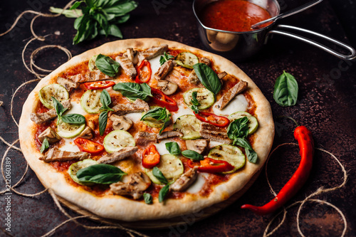 Pizza with slices of meat with basil and pepper